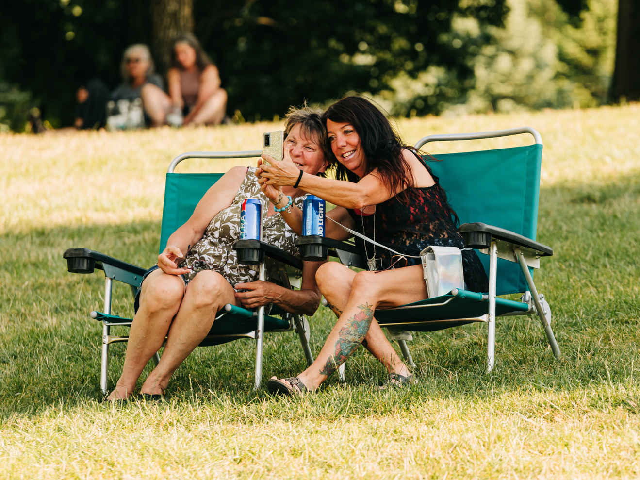 Two fans sitting in lawn chairs in the lawn section.